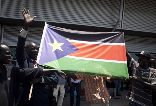 ISRAEL OUT South Sudanese migrants wave their national flag as they wait to board a bus to Ben Gurion Airport, near Tel Aviv, where they will be deported to south Sudan on June 17, 2012. Some 120 people from Southern Sudan will take the first flight back home as part of a nationwide crackdown to expel thousands of illegal African migrants from Israel. AFP PHOTO / OREN ZIV / ACTIVE STILLS (Photo credit should read OREN ZIV/AFP/GettyImages)