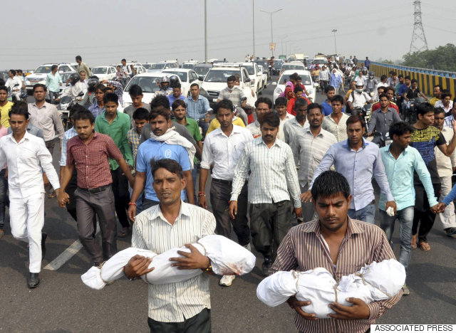 Relatives carry the bodies of a baby and a toddler killed in a house fire allegedly set by their family's upper caste neighbors, as angry residents block a highway in Faridabad near New Delhi, India, Wednesday, Oct.21, 2015. 
