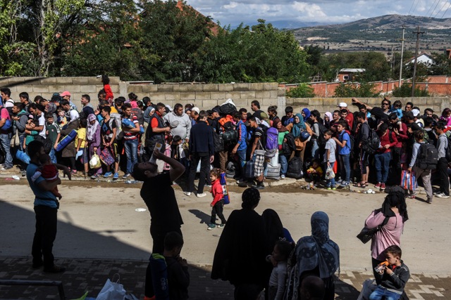 Migrants and refugees wait for a bus after arriving in the village of Miratovac near the Serbia-Macedonian border, on September 11, 2015. A record 5,000 migrants have arrived at Serbia's border with Hungary over the past 24 hours, a television report said on September 10. The EU unveiled plans to take 160,000 refugees from overstretched border states, as the United States said it would accept more Syrians to ease the pressure from the worst migration crisis since World War II. AFP PHOTO / ARMEND NIMANI