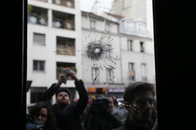 Journalists work outside a restaurant where bullet impacts are seen the day after a series of deadly attacks in Paris, France, November 14, 2015. REUTERS/Gonzalo Fuentes