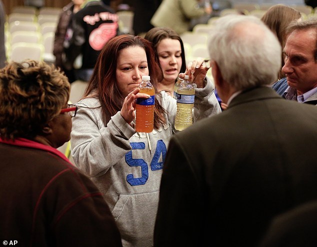 FILE - In this January 21, 2015 file photo, LeeAnne Walters of Flint, Mich., shows water samples from her home from Jan. 21, 2015 and Jan. 15, 2015 to Flint's emergency manager Jerry Ambrose after city and state officials spoke during a forum discussing growing health concerns being raised by Flint residents at the Flint City Hall dome. Since the financially struggling city broke away from the Detroit water system last year, residents have been unhappy with the smell, taste and appearance of water from the citys river as they await the completion of a pipe to Lake Huron. They also have raised health concerns, reporting rashes, hair loss and other problems. A General Motors plant stopped using the water, saying it was rusting its parts. (AP Photo/Detroit Free Press, Ryan Garza)