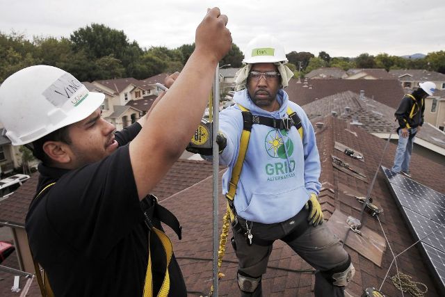 William Arreola, (left) The Rising Sun Energy Center job training program is instructed by roof supervisor, Frank Ross with Grid Alternatives, as they install solar panels on the roof of a home in Richmond, California.