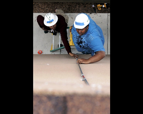 Alfonso Martinez, (left) and Rodney Tolliver, with The Rising Sun Energy Center job training program install conduit up the side of the house to bring wiring to the solar panels on a home in Richmond, California.