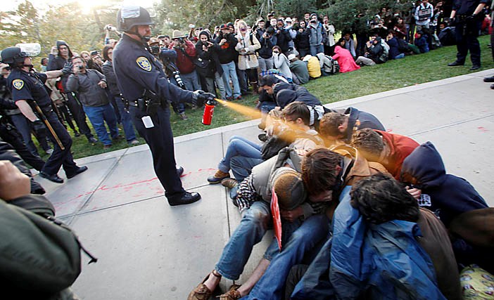 UC Davis Police Lt. John Pike uses a can of pepper spray to move protestors who were blocking officers attempts to remove arrested protestors from the Quad on Friday afternoon. Wayne Tilcock/Enterprise photo