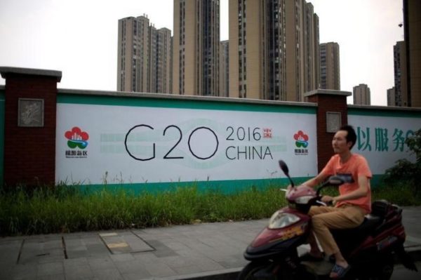 A man rides an electronic bike past a billboard for the upcoming G20 summit in Hangzhou