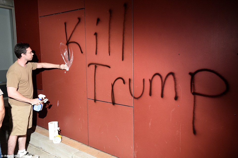 Oakland: A member of the public tries to scrub away 'Kill Trump' graffiti as demonstrators riot in California
